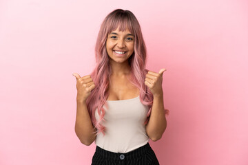 Obraz na płótnie Canvas Young mixed race woman with pink hair isolated on pink background with thumbs up gesture and smiling