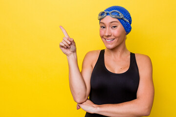 Young australian swimmer woman isolated on yellow background smiling cheerfully pointing with forefinger away.