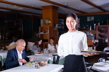 Fototapeta na wymiar portrait of happy female garson standing in cafe
