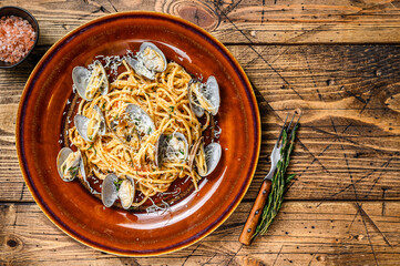 Obraz na płótnie Canvas Italian seafood Spaghetti pasta with clams in a rustic plate. Wooden background. Top view. Copy space
