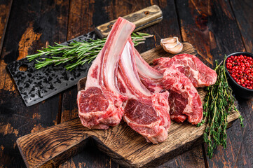 Lamb raw chops  steaks on butcher cutting board. Dark wooden background. Top view