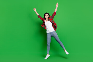 Full size photo of joyful brunette hairdo young lady jump wear red shirt jeans isolated on green color background