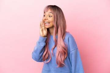 Young mixed race woman with pink hair isolated on pink background shouting with mouth wide open to the side