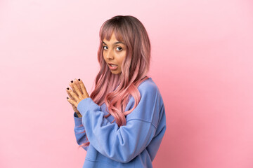 Young mixed race woman with pink hair isolated on pink background scheming something