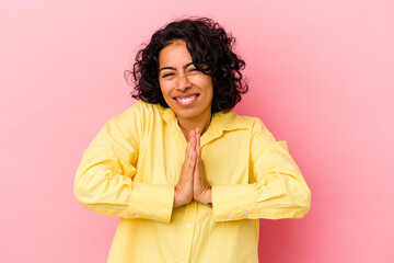 Fototapeta na wymiar Young curly latin woman isolated on pink background holding hands in pray near mouth, feels confident.