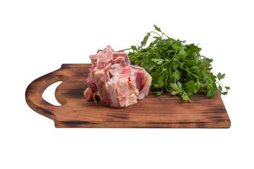 Chunks of fresh raw beef oxtail meat on a wooden board with a bunch of parsley isolated on a white background