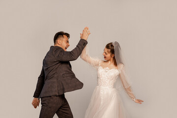 Fototapeta na wymiar excited newlyweds giving high five isolated on grey with lilac shade