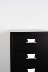 Small metal cabinet detail with two drawers and white drawer labels, set against a plain white wall
