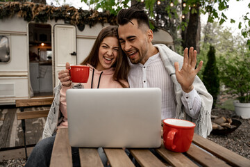 cheerful couple waving hands during video call in camping