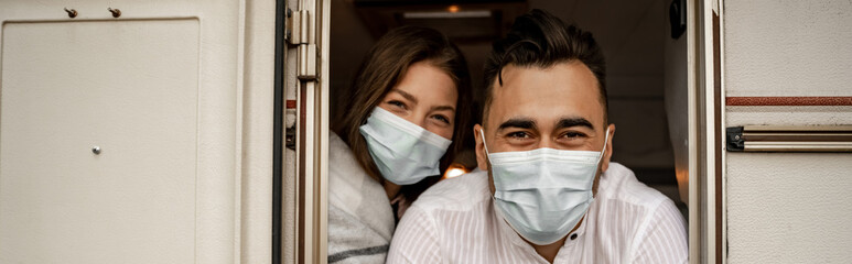 young couple in protective masks looking out trailer, banner