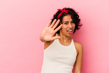 Young curly latin woman isolated on pink background rejecting someone showing a gesture of disgust.