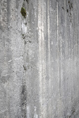 Coarse angled concrete wall with moss growth and water runoff marks