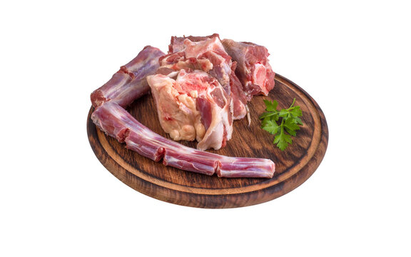 Whole fresh raw beef tail chopped into pieces on round wooden board isolated on white background
