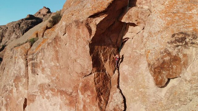 Young woman climbing on the high rock