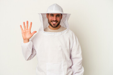 Young apiculture caucasian man isolated on white background smiling cheerful showing number five with fingers.