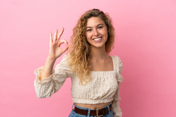 Young blonde woman isolated on pink background showing ok sign with fingers