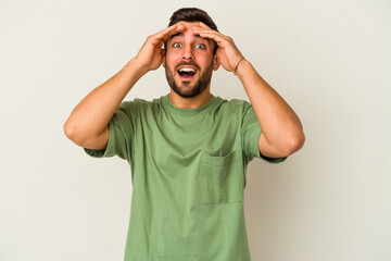 Fototapeta premium Young caucasian man isolated on white background laughs joyfully keeping hands on head. Happiness concept.