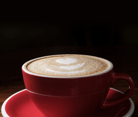 Coffee cup on dark background with copyspace. Latte art o9n top froth