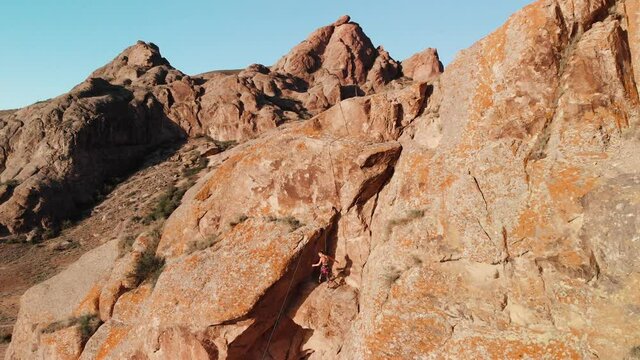 Young woman climbing on the high rock