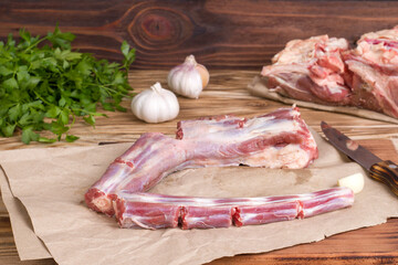 Whole fresh raw beef tail sliced into pieces on wooden background - obrazy, fototapety, plakaty