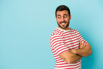 Young caucasian man isolated on blue background smiling confident with crossed arms.