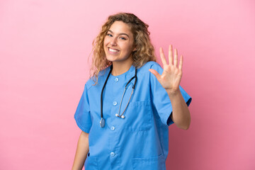 Young surgeon doctor woman isolated on pink background counting five with fingers