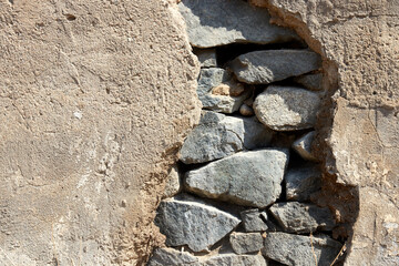 a large crack with fallen plaster of an old abandoned stone house