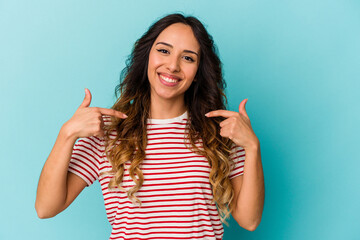Young mexican woman isolated on blue background surprised pointing with finger, smiling broadly.