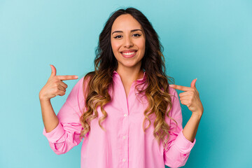 Young mexican woman isolated on blue background points down with fingers, positive feeling.