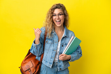 Young student caucasian woman isolated on yellow background pointing to the side to present a product