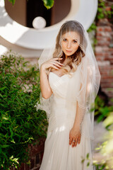 bride with long wavy hair in the garden. Wedding make-up. 