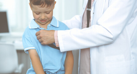 Happy smiling male kid-patient at usual medical inspection. Doctor and young boy in the clinic. Medicine concepts