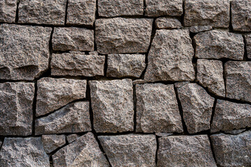 Closeup front view of a massive stone wall with sharp lines outdoors.