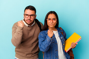 Fototapeta premium Young mixed race student couple isolated on blue background showing fist to camera, aggressive facial expression.