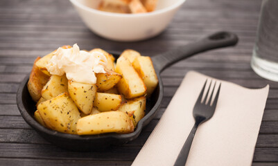 Spanish traditional appetizer patatas bravas with alioli sauce on small cast iron skillet