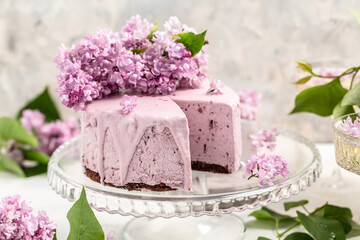 Obraz na płótnie Canvas velvet mousse cake with blueberries decorated with a bouquet of purple blooming lilac, French cuisine, postcard, background