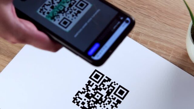 Hand holding smart phone to scan QR code payment. The concept of cashless technology or digital payment.