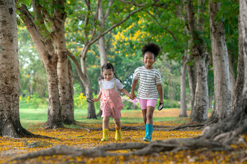 Naklejka na ściany i meble Two little girls of different skin colors hold hands and take a walk in the park on a beautiful summer day, Diverse friends