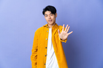 Young Chinese man isolated on purple background counting five with fingers