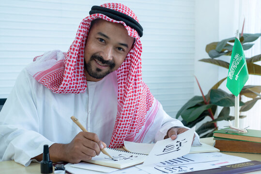 Arab men practicing writing Arabic ้with bamboo pens and ink on paper, Arabic letters mean the name of Muslim god "Allah", handwriting Khat, looking at camera