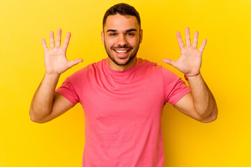 Young caucasian man isolated on yellow background showing number ten with hands.