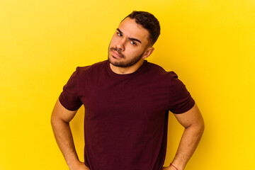 Young caucasian man isolated on yellow background frowning face in displeasure, keeps arms folded.