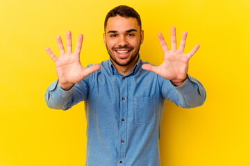 Young caucasian man isolated on yellow background showing number ten with hands.
