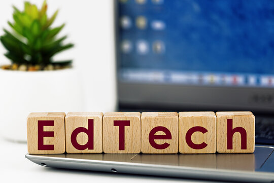 photo on EdTech theme. wooden cubes with the words "EdTech",  on the background of laptop and succulent