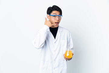 Young Chinese scientific man isolated on white background making phone gesture. Call me back sign