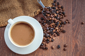 cup of coffee and coffee beans in a sack on  Brown background, top view