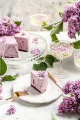 Obraz na płótnie Canvas a piece of mousse cake, Delicious dessert blueberry tart with fresh berries with a bouquet of purple blooming lilacs, vertical image place for text