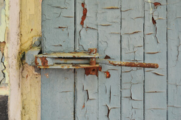 A close up of a shed latch in a grainy blue gray door