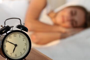 Sleepy young woman stretching hand to ringing alarm willing turn it off. Early wake up, not getting...