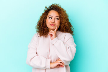 Young latin curvy woman isolated on blue background contemplating, planning a strategy, thinking...
